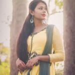 Portrait of a young woman in traditional Indian dress surrounded by trees, exuding elegance and grace.